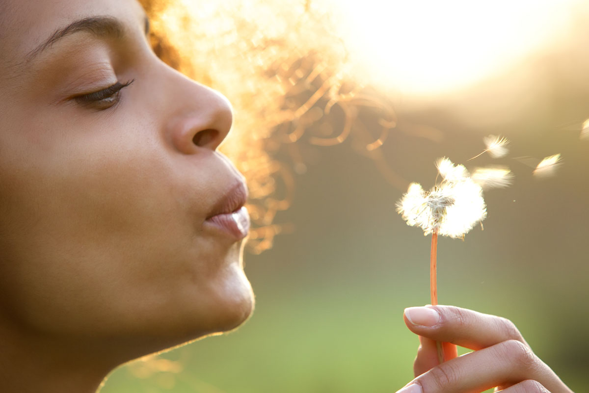 beautiful-young-woman-blowing-dandelion-flower