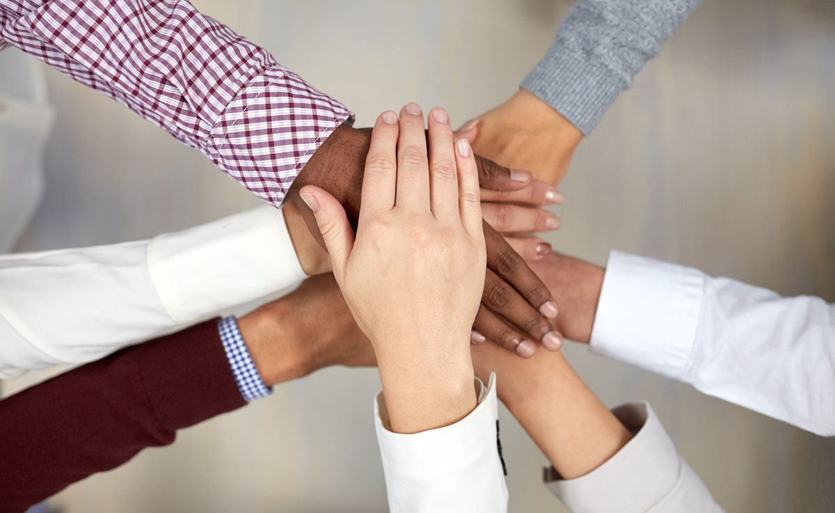  business-team-with-hands-on-top-at-office